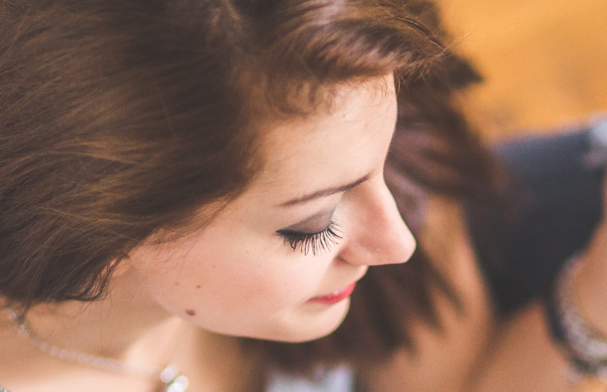 Close-up photo of a model taken from above and to the side of their head showing off their makeup and eye lashes.