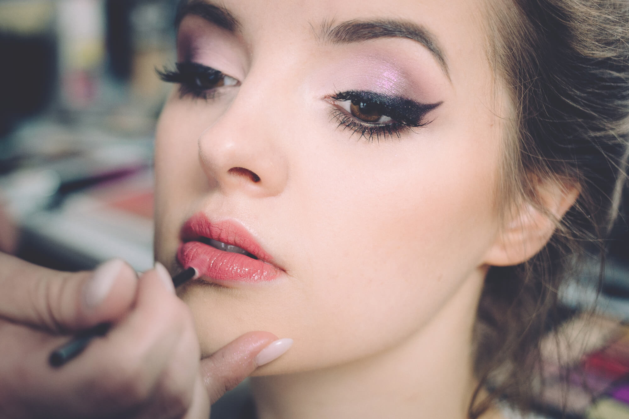 Close-up of professional model having makeup applied to their lips.