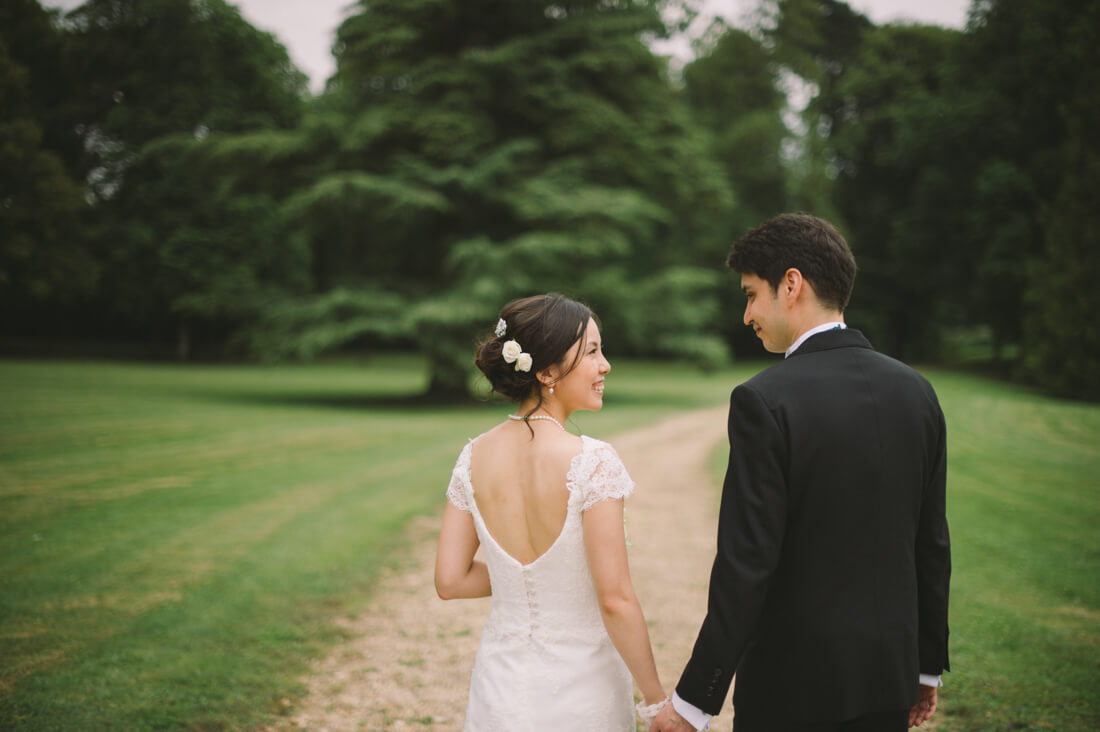 Happy bride and groom walking hand in hand down a track in an orchard.
