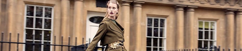 Blonde model in a 1950's to 1960's style hair and makeup walking in from of bath stone houses.