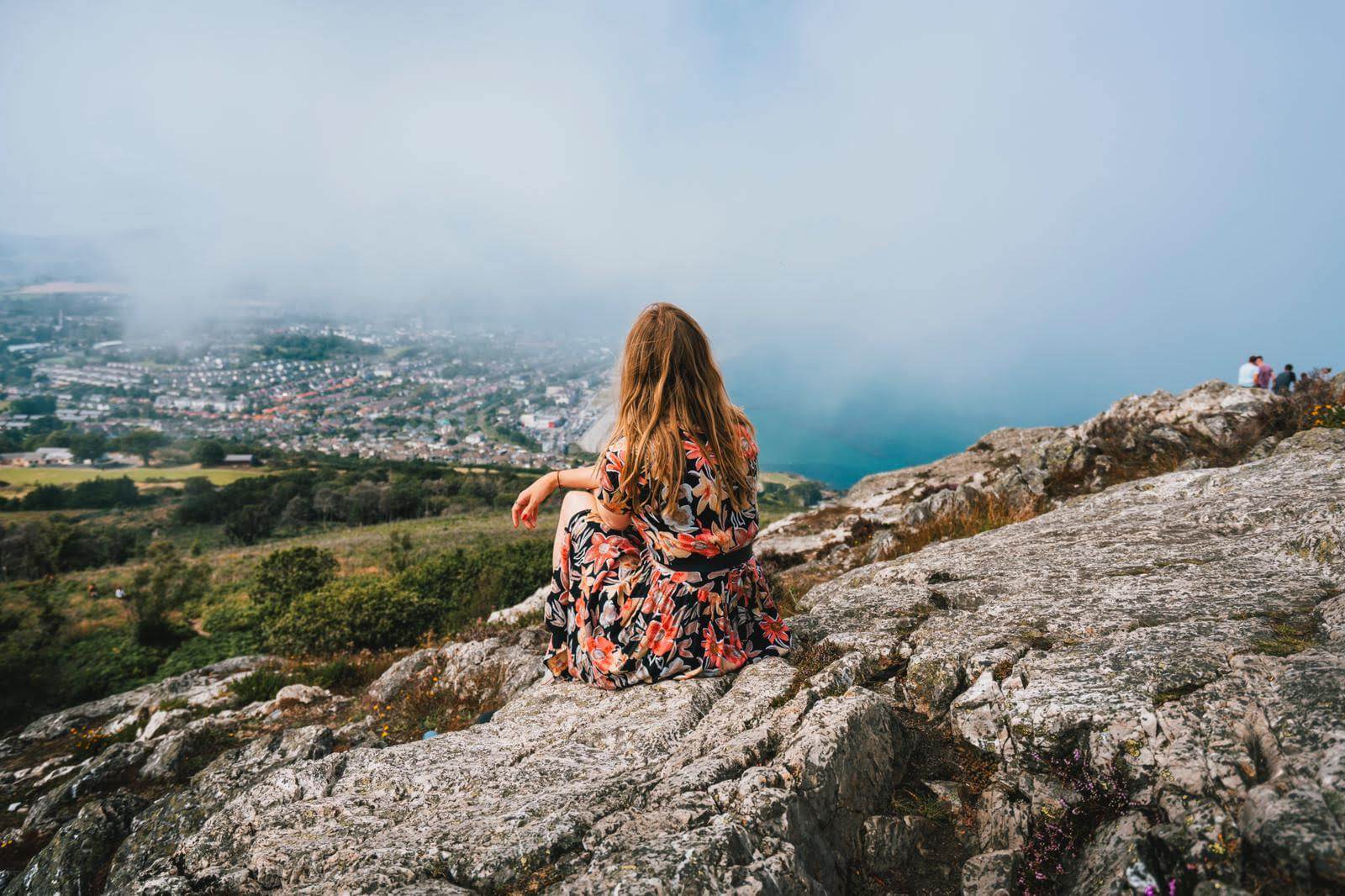 Professional makeup artist Evie Sith sitting on a high rock ledge in Costa Rica looking out at the stunning view on the horizon.