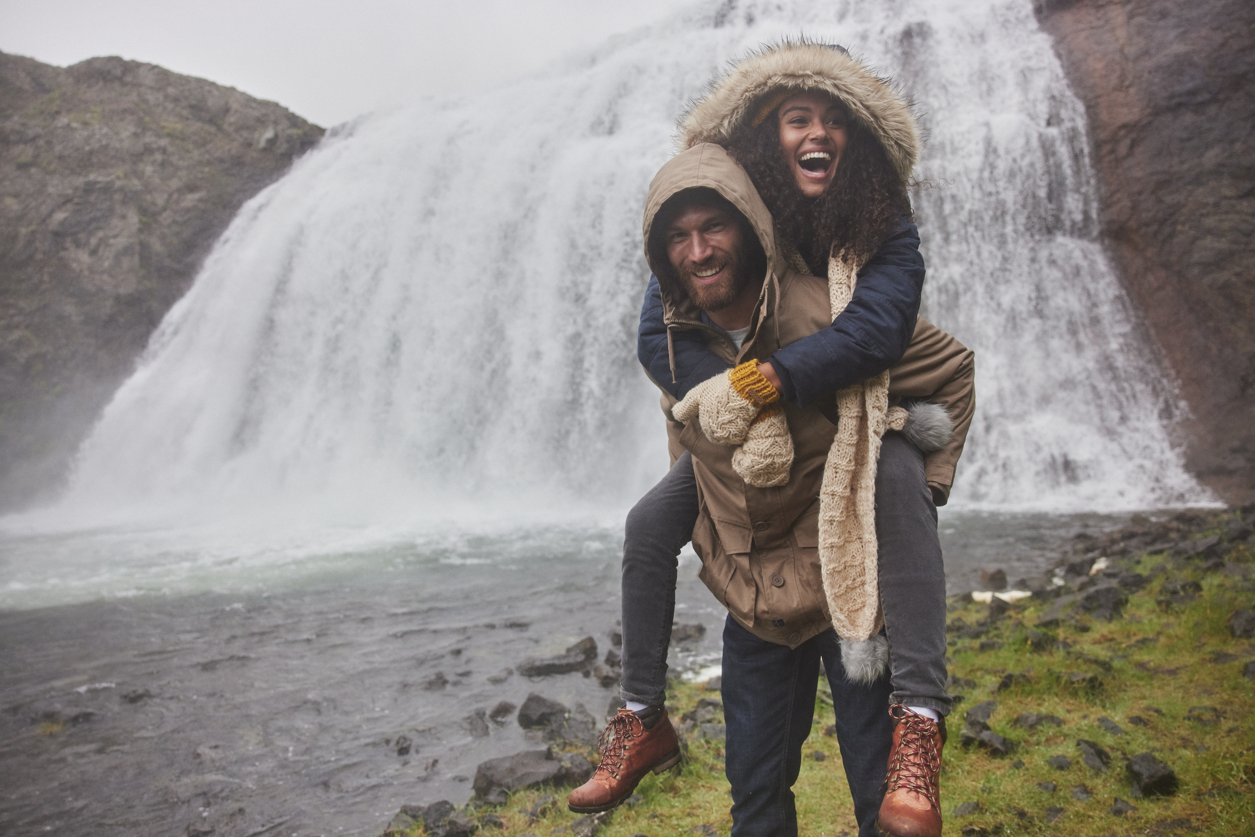 Models looking happy posing in front of a waterfall in Iceland shooting for Weird Fish with makeup by Bristol makeup artist Evie Smith.