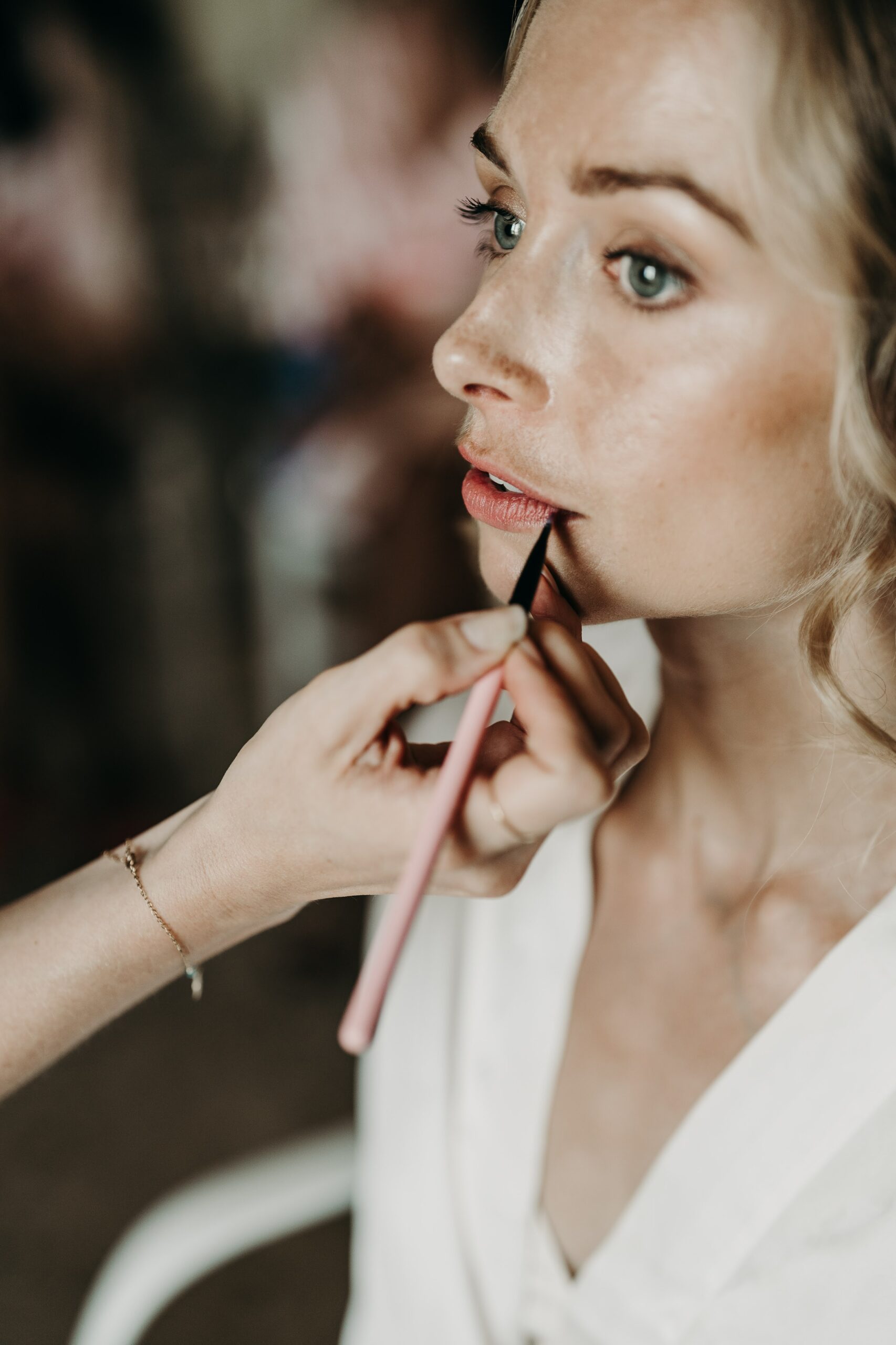 Destination wedding hair and makeup artist Evie Smith applies makeup to a bride's lips in a closeup shot of her wedding in Puglia.