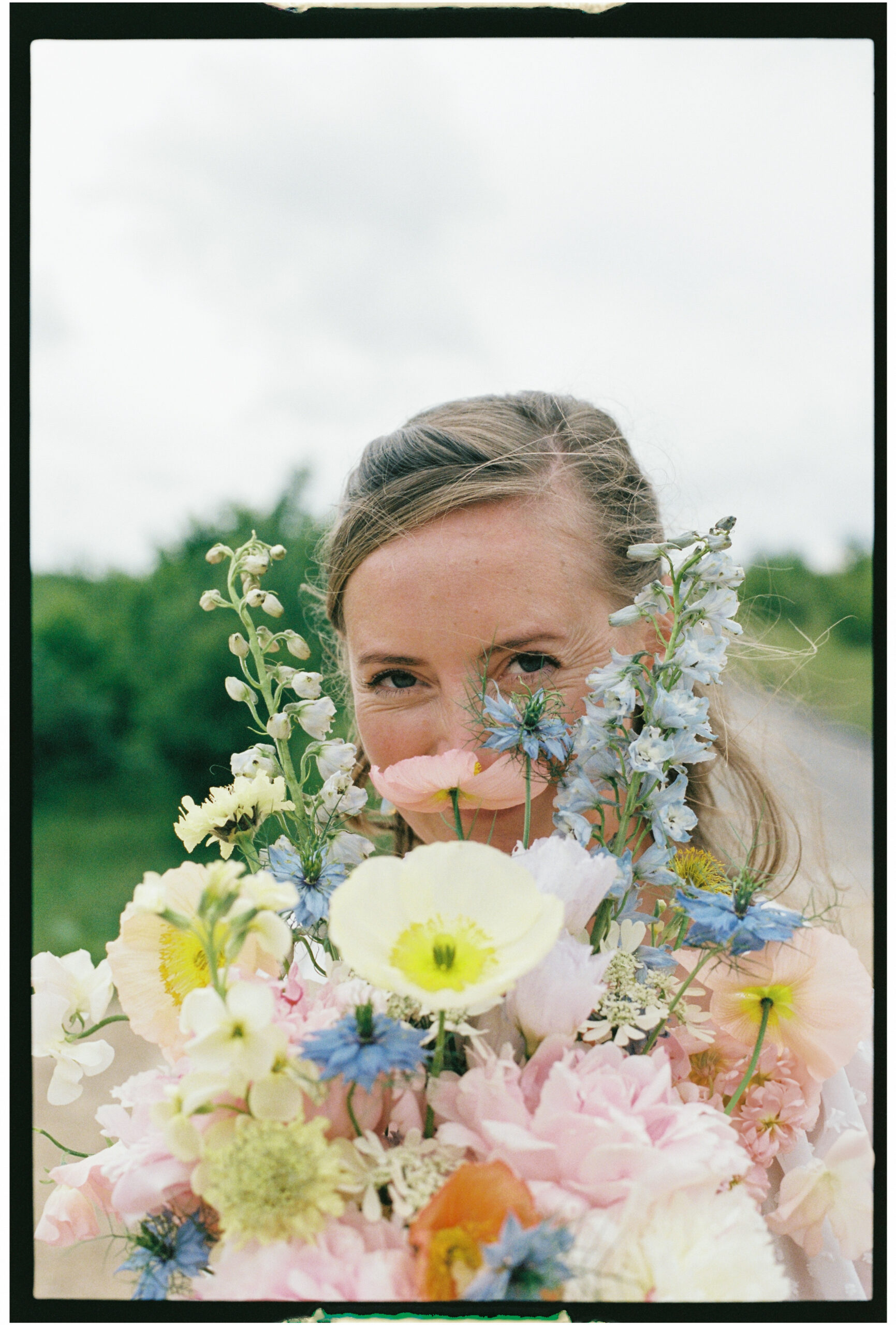 a fair haired woman holding a bouquet of flowers on her wedding day. She is looking straight at the camera and smiling.